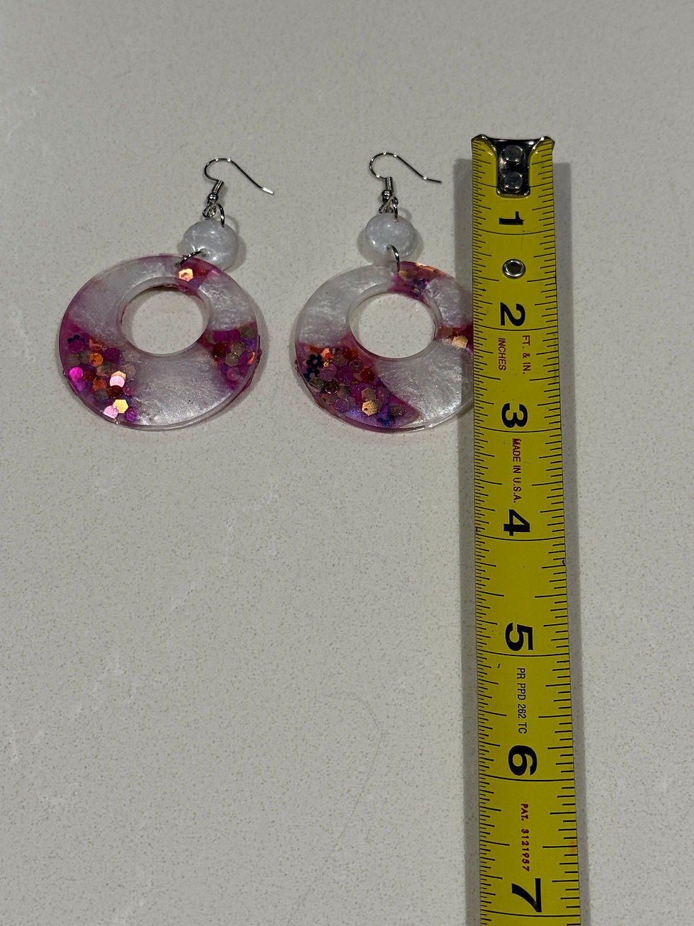 Thumbnail: handmade pink and white resin circle earrings next to ruler showing approximately 2.5 inch length