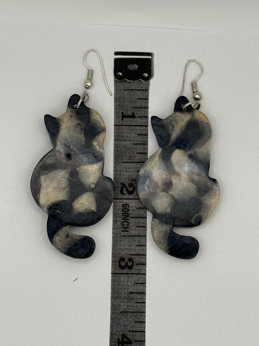 Handmade resin cat earrings displayed next to ruler showing approximate size and scale