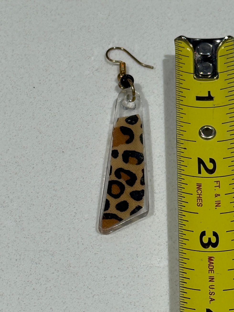 Thumbnail: Leopard print resin earring next to ruler showing approximate size and length