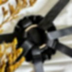 Close-up of the Dahlia Strap-On Harness by Velvet Nest, featuring black cotton straps and a feminine ruffle O-ring detail on