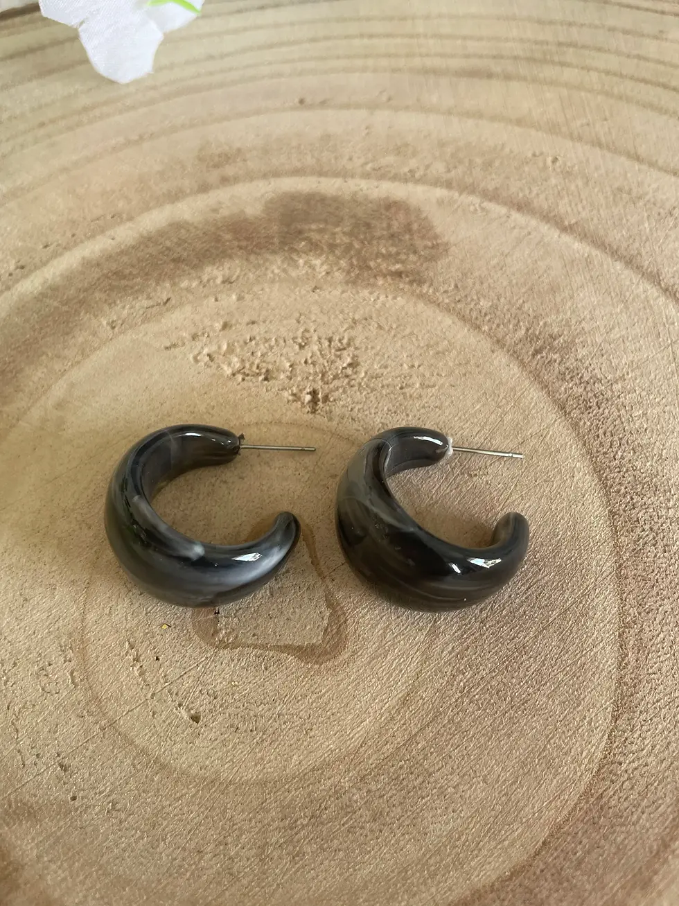 Boucles d'oreilles créoles noires sur fond bois, Bijoumaey - Bijoux en pate fimo.