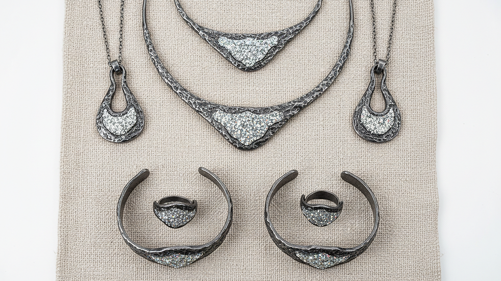 Vue en plongée d’une collection de bijoux artisanaux français sur un tissu naturel