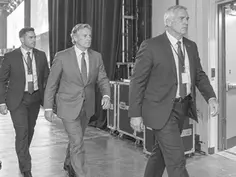 Executive escorted backstage by two security coordinators on the way to the conference stage