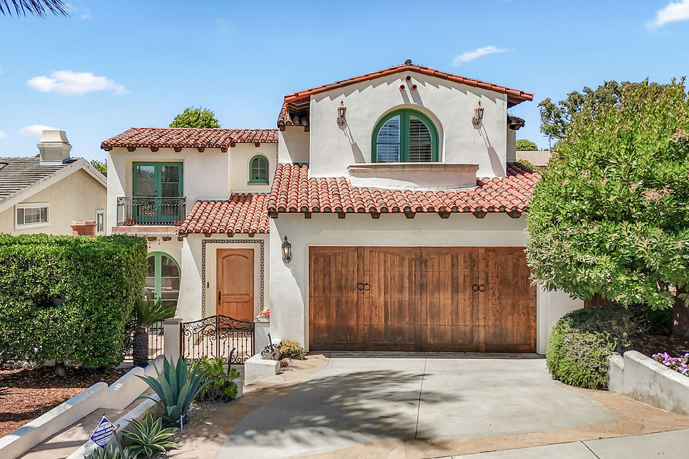 Spanish-style home with red tile roofs, green-trimmed windows and wood entry and garage doors at 1337 Eighth Street in Manhattan Beach.