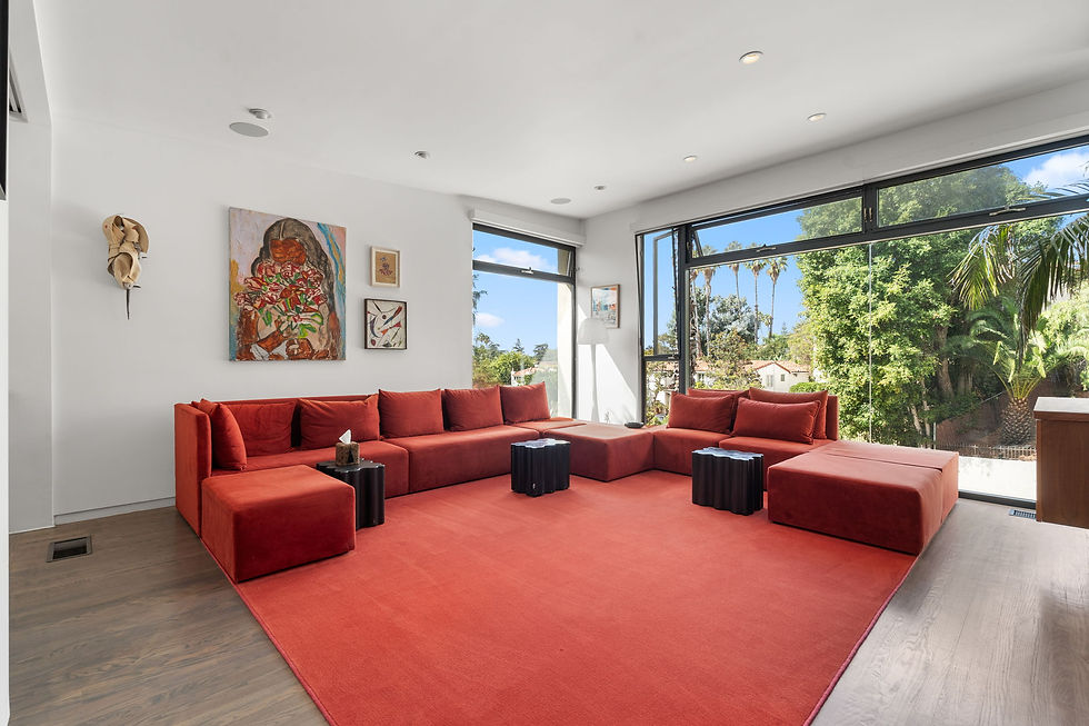 Red sectional seating and a matching rug beside large garden-facing windows at 2240 N New Hampshire Avenue in Los Feliz.