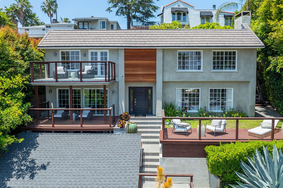 Elevated daytime exterior of 6609 Whitley Terrace showing the two-story facade, layered wood decks and landscaped hillside lot