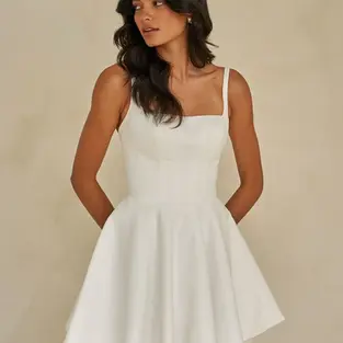Crafted in luxurious satin, this sweet mini wedding dress is perfect for the minimalist bride. But who also wants timeless elegance with a fashion-forward edge.

Featuring a structured corset bodice with exposed boning, a clean square neckline, and a flattering Basque waistline. Waverly-Mae sculpts the figure for a cinched, tailored silhouette that feels both polished and playful.

Designed for versatility, this style invites personalisation—pair it with the Waverly-Mae satin overskirt for a striking contrast of textures. Or, mix and match with veils and accessories to create a bridal look that’s uniquely your own.

From ceremony to celebration, Waverly-Mae is a statement mini with endless styling possibilities.