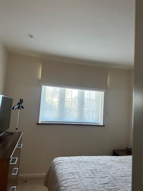 Bedroom with a bed, dresser, and sunlit window with blinds.