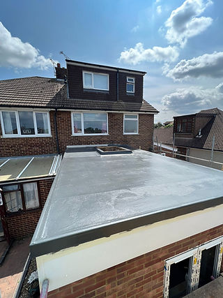 Flat roof extension with fresh gray coating in a suburban area under a blue sky
