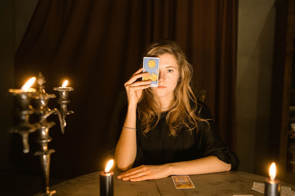 A blonde woman holding a tarot card over her eye