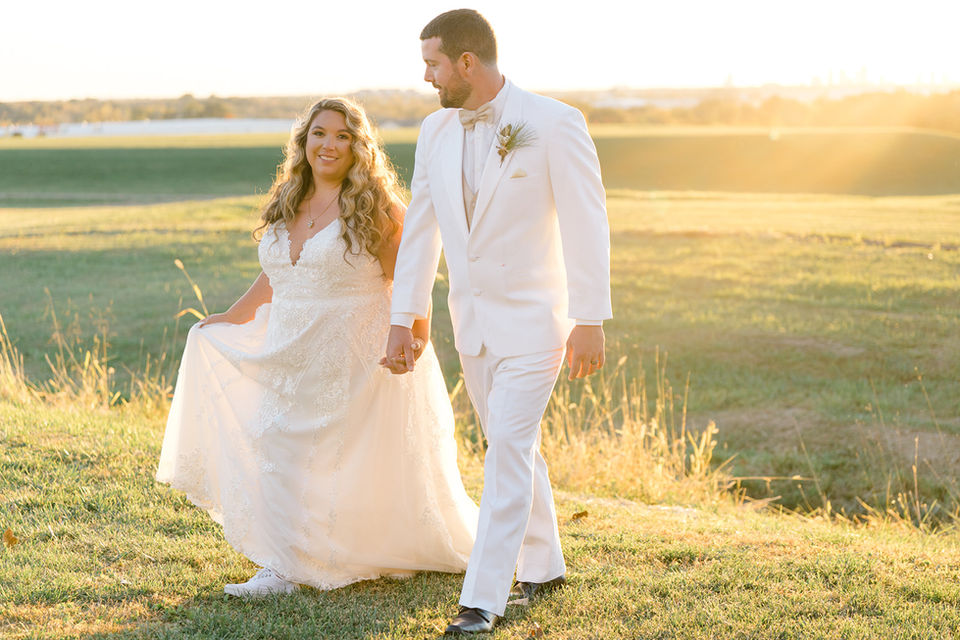 Sunset behind couple walking in grass.