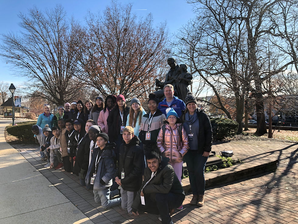 Deaf Middle School students pose for photo in front of a statue.