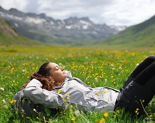 Hiker resting lying on the grass in a valley of a high mountain.jpg
