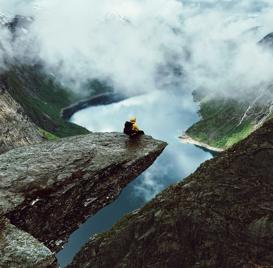 man-sits-end-trolltunga-before-mountains.jpg