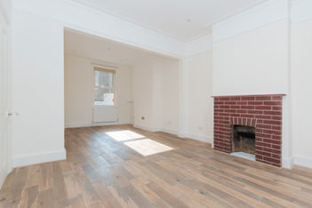 White-painted open-plan space with red brick fireplace on right