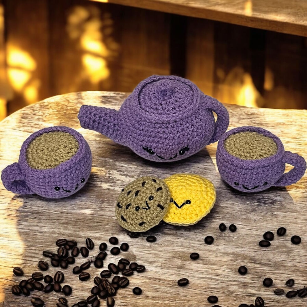 Handcrafted crochet tea set, a blue teapot, two matching teacups, and two smiling cookie plushies on a light background.