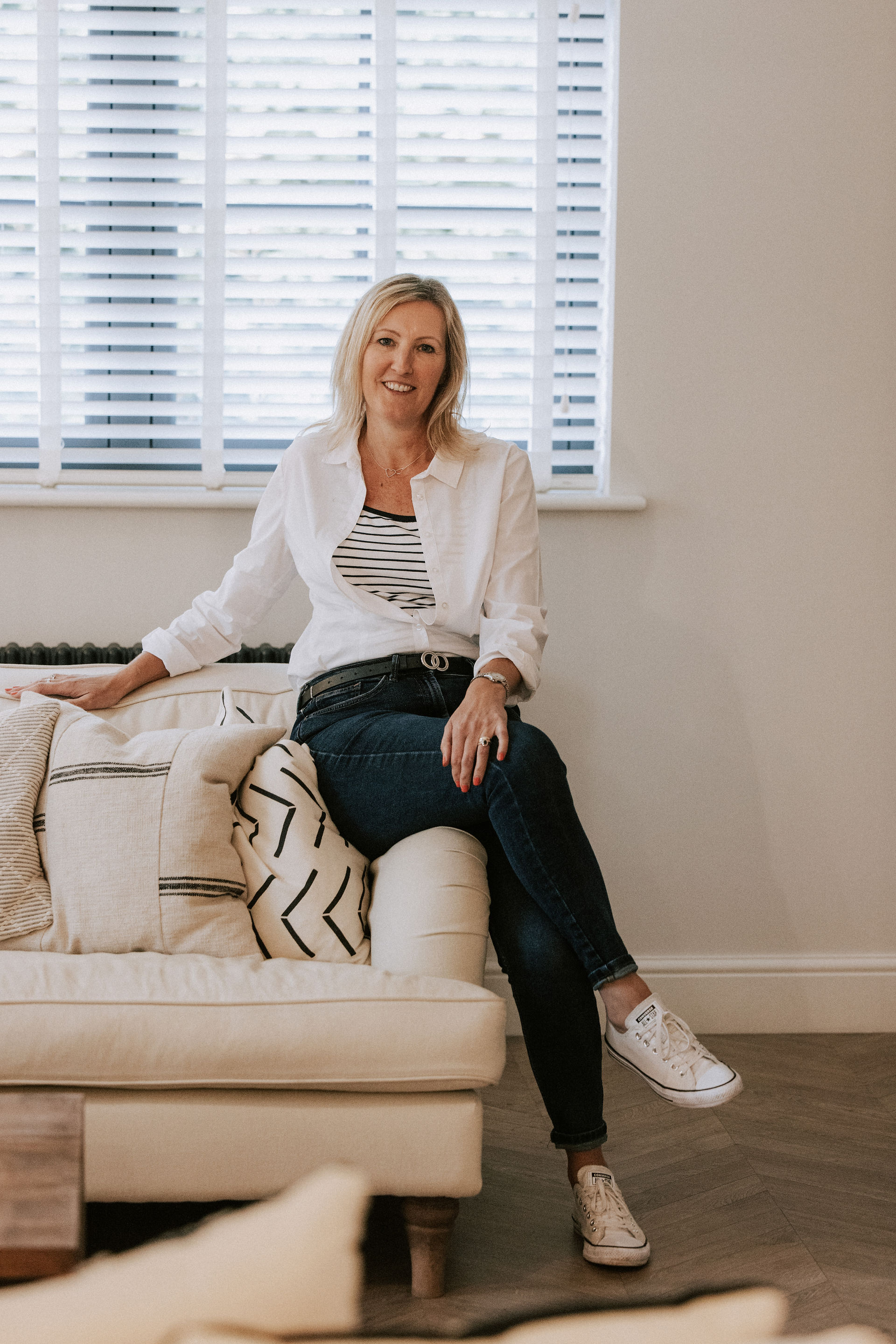 Kelly Hawes sitting on the edge of a couch ready to chat about weddings