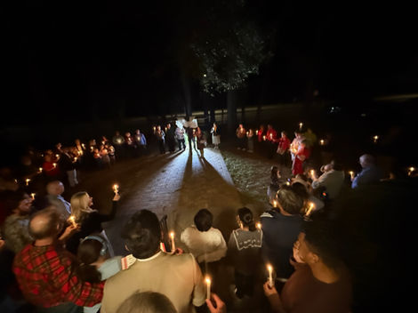 people circled around the outside of the church holding candles.
