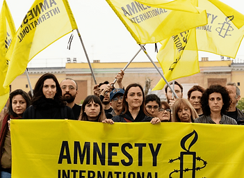 A group of people holding yellow Amnesty International banners and waving Amnesty International flags