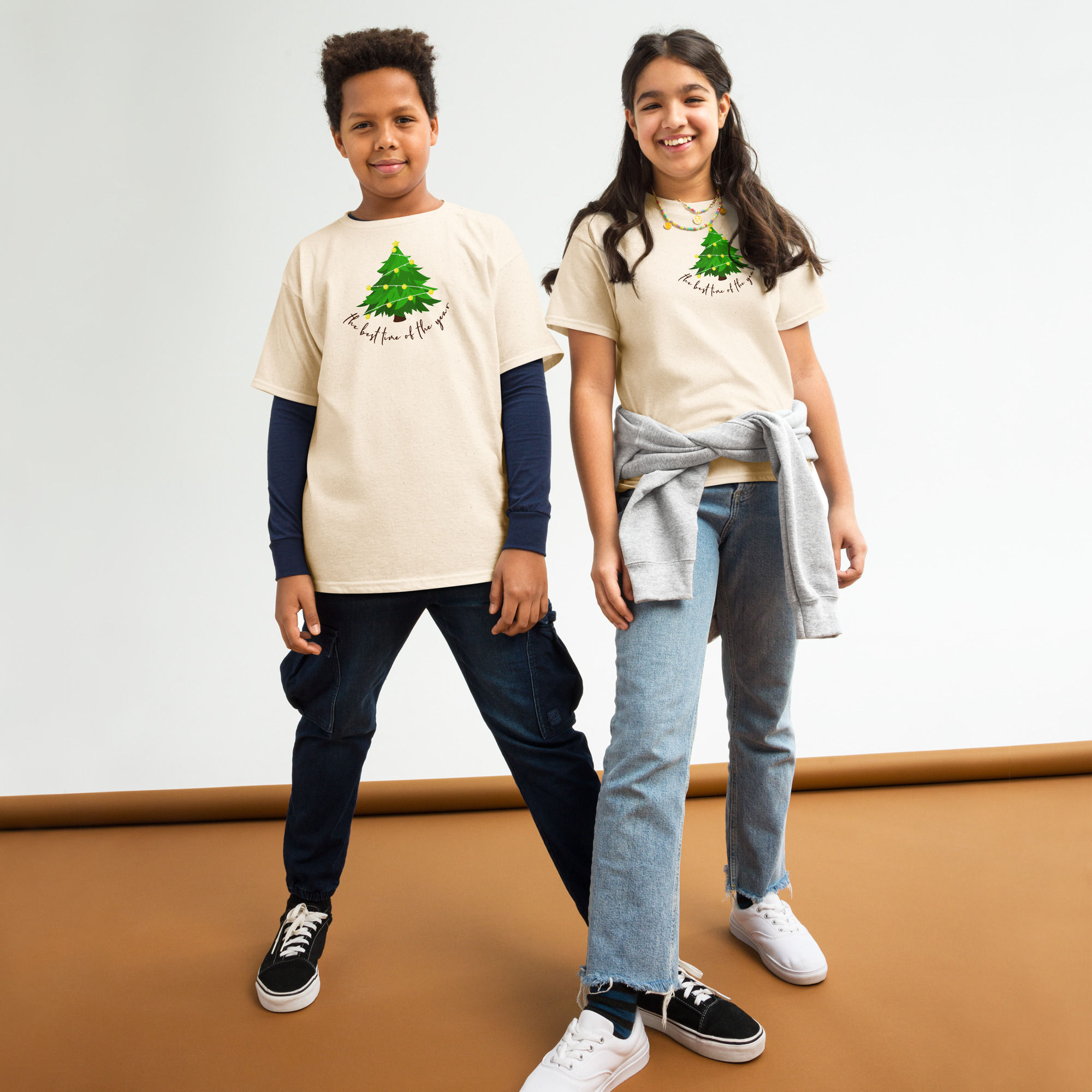 Front view of a boy and a girl dressed in a Christmas T-shirt designed with a green Christmas tree with Christmas inscription