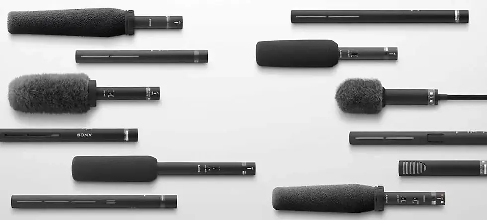 Multiple different shotgun microphones laid flat on a white background.