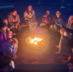 women travelers together around a bonfire cooking smores