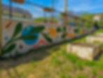 Vegetables, bugs, and circles come together to create a small mural located at a community garden.