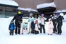 Family with two ski instructors throwing snowballs in front of the Kiroro Mountain Centre, Hokkaido, Japan.