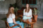 Yogatherapie-Einzelsession: Therapeutin im Gespräch mit Klientin in ruhiger, natürlicher Umgebung mit Holzmöbeln und Pflanzen – achtsames Setting für persönliche Begleitung und Heilung