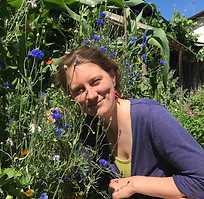 Frau schaut hinter Blumen hervor, Yogatherapie Kursteilnehmerin