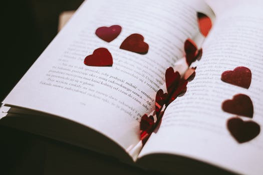 Open book with red metallic hearts lying in it
