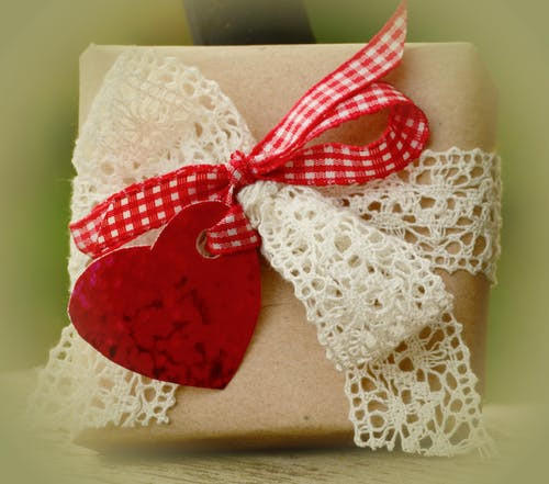 Gift wrapped in brown paper and tied with cream lace and red gingham bow and a red heart tag