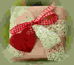 Gift wrapped in brown paper and tied with cream lace and red gingham bow and a red heart tag