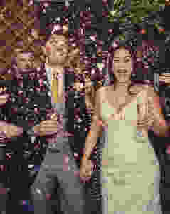 Bride and groom showered in confetti and drinking champagne