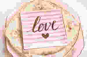 The word love printed on a square china plate sitting on floral vintage china plates