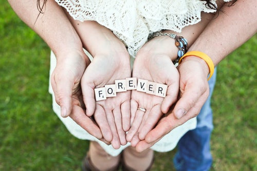 A couple's hands holding Scrabble letters which spell the word Forever