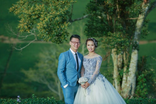 Smiling bride and groom in matching blue wedding dress and suit