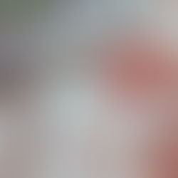 A person writing in a journal on a desk, with a candle, a plant and a cup