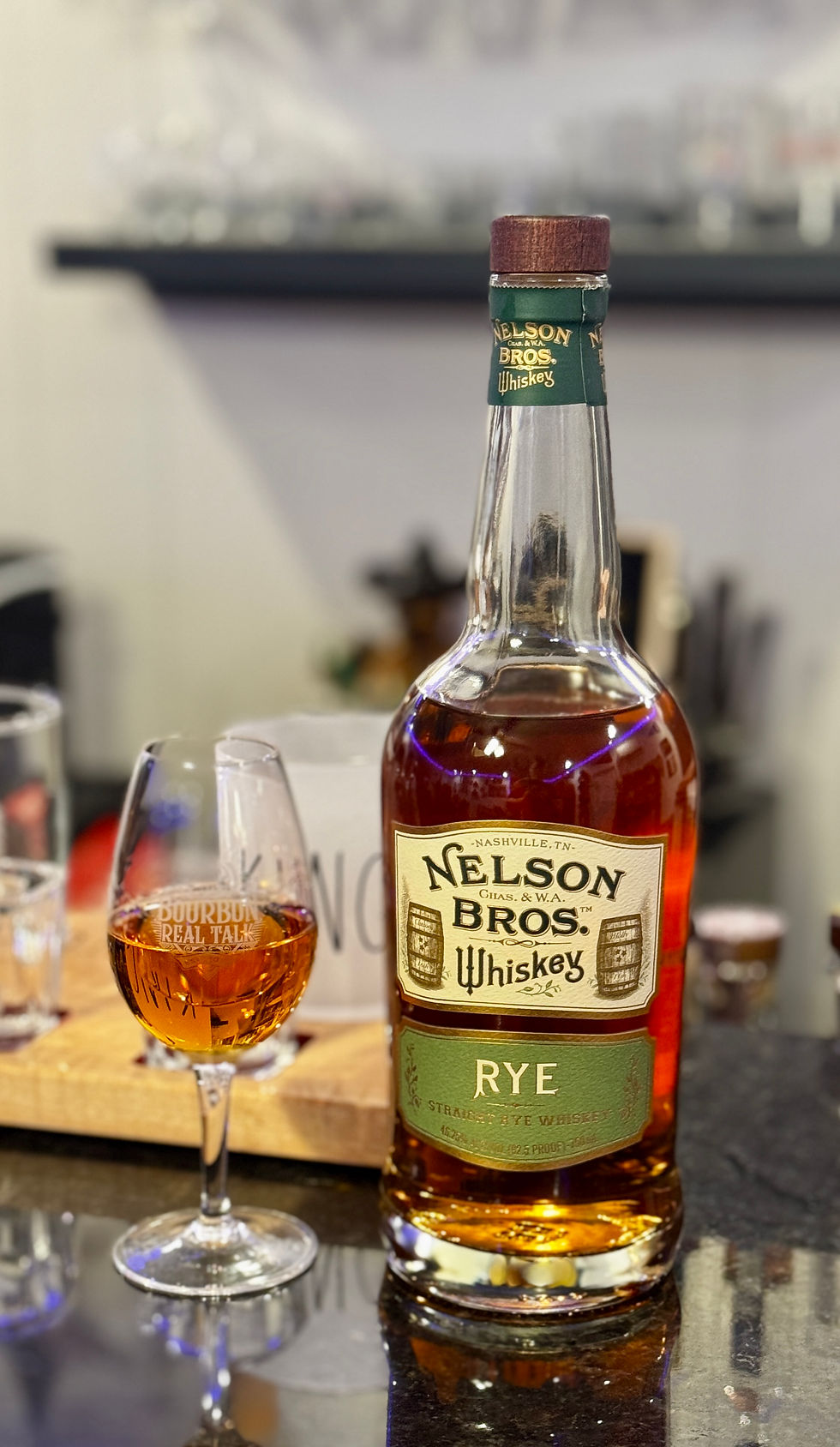 A Bottle of Whiskey alongside a whiskey tasting glass.