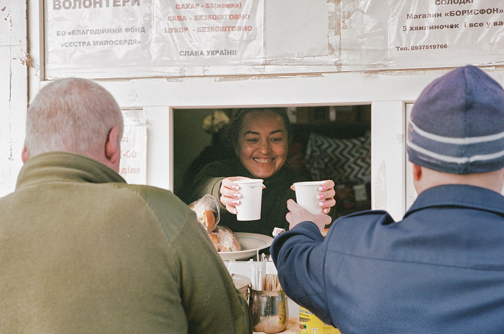Yarina Chagovets hands out coffee and bread rolls to wounded soldiers through the window of the Sister of Mercy volunteer space at the military hospital in Kharkiv, April 2026.