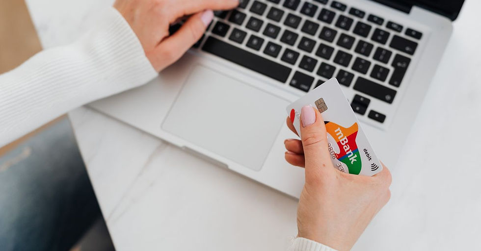 Close-up of a person using a laptop and holding a credit card for online shopping.