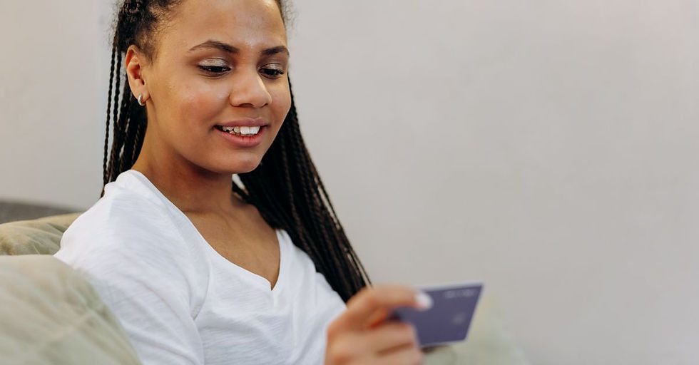 A woman in a white shirt smiling while holding a credit card indoors, showcasing modern banking convenience.