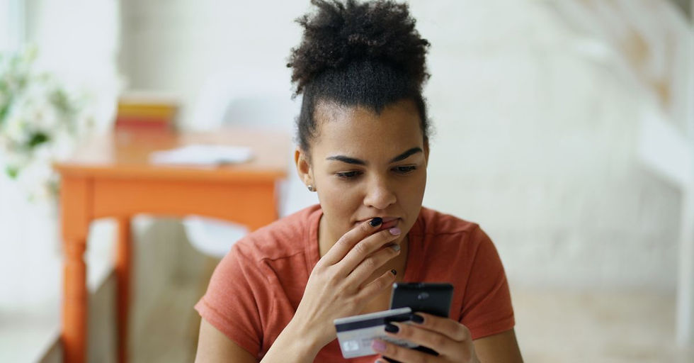 Young woman shopping online using a smartphone and credit card indoors.