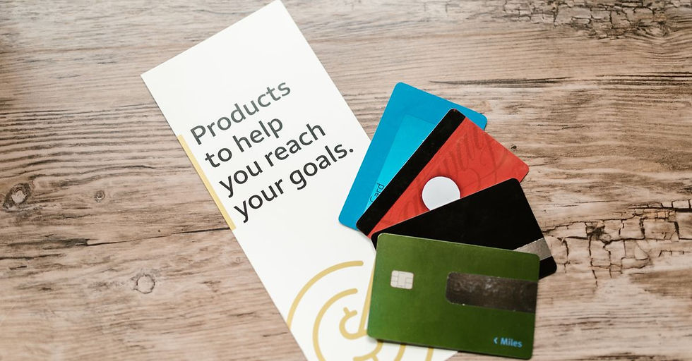 Assorted credit cards on a wooden table next to a leaflet with motivational text about financial goals.