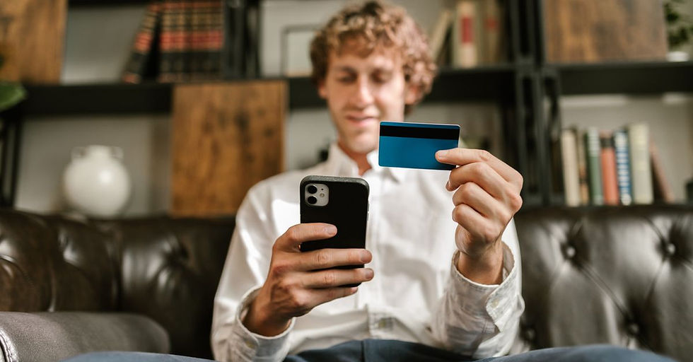 A man smiles while using his smartphone and credit card for online shopping.