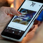 Woman using smartphone for online shopping with credit card in hand, festive background lighting.