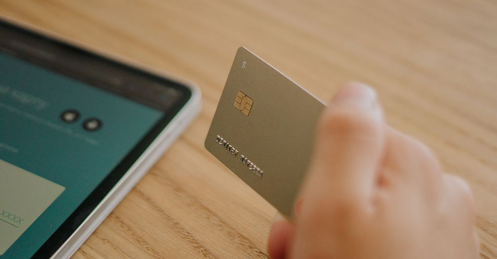 Close-up of a hand holding a credit card near a tablet, depicting online shopping or transaction.
