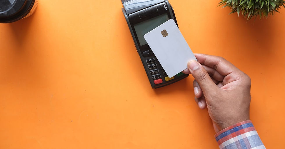 A person holding a blank credit card near a payment terminal on orange
