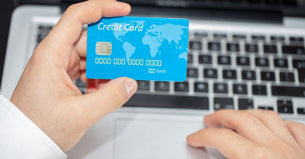 Person holding credit card near laptop for online shopping, emphasizing secure online transactions.