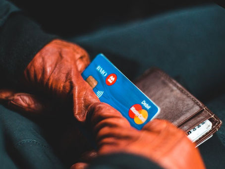 Close-up of hands in gloves holding a credit card and wallet indoors.